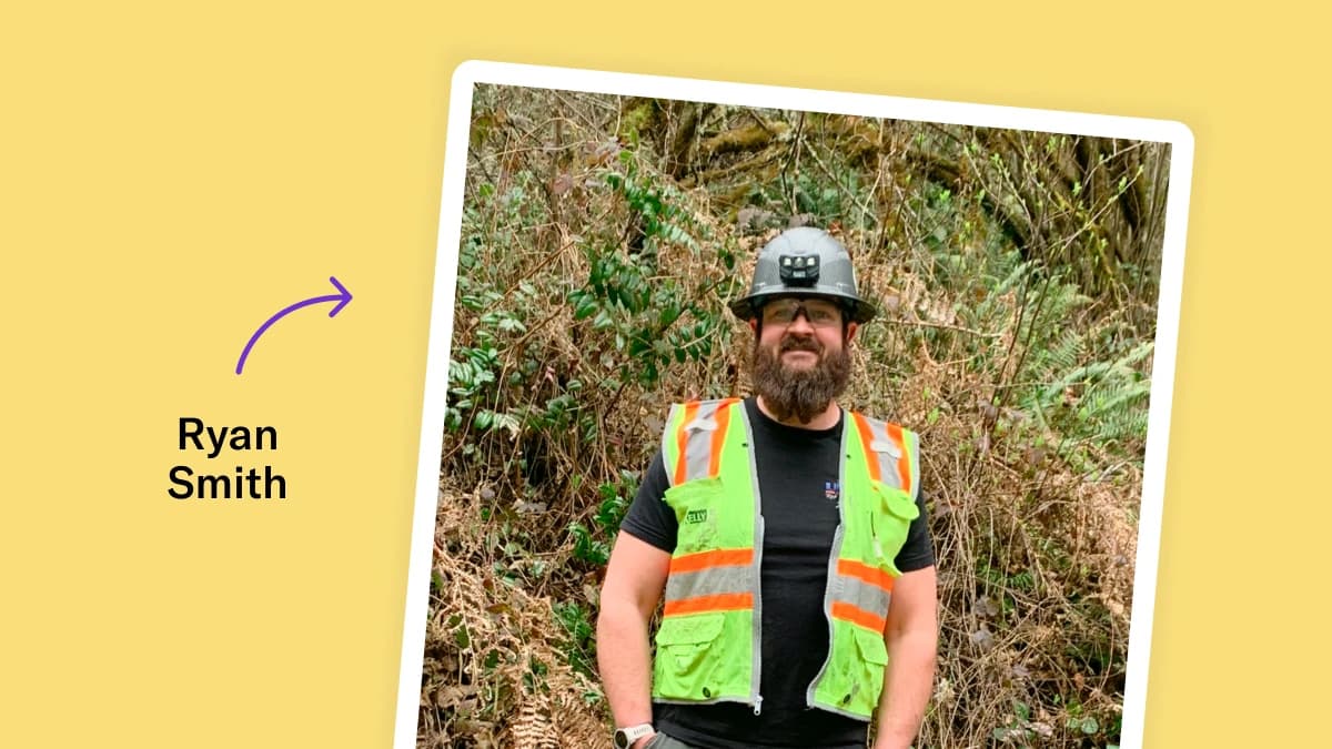 Polaroid-style photo of Ryan Smith on a yellow background. He is wearing a gray hardhat, safety glasses, a black t-shirt, and a bright green high-vis vest.
